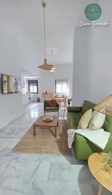 a living room with a green couch and a table at Apartamentos Turísticos Juan Grande by Sanlúcar Housing in Sanlúcar de Barrameda