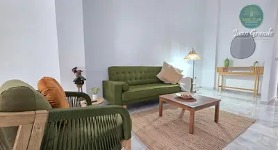 a living room with green couches and a coffee table at Apartamentos Turísticos Juan Grande by Sanlúcar Housing in Sanlúcar de Barrameda