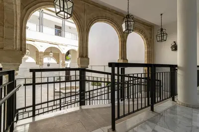 a hallway with arches and a black railing at Casa Palacio Marqués de Castellanos in Jerez de la Frontera