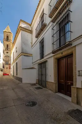 an alley with a building with a door and a clock tower at Casa Palacio Marqués de Castellanos in Jerez de la Frontera
