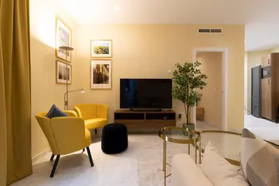 a living room with a television and yellow chairs at Casa Palacio Marqués de Castellanos in Jerez de la Frontera