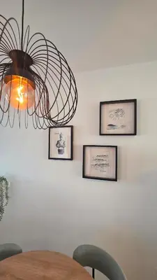 a chandelier hanging over a table with pictures on the wall at La San Sebastián del Sur by Sanlúcar Housing in Sanlúcar de Barrameda