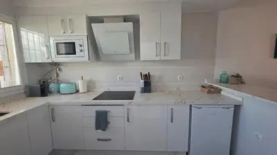 a white kitchen with white cabinets and a microwave at La San Sebastián del Sur by Sanlúcar Housing in Sanlúcar de Barrameda