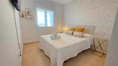 a bedroom with a white bed with a table at La San Sebastián del Sur by Sanlúcar Housing in Sanlúcar de Barrameda