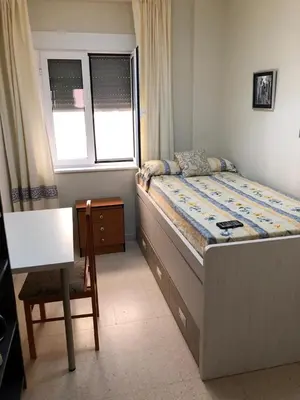 a bedroom with a bed and a chair and a window at Playa, Sol y Relax in Cádiz