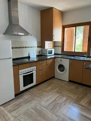 a kitchen with a white refrigerator and a dishwasher at Apartamento planta baja con jardín privado in Novo Sancti Petri