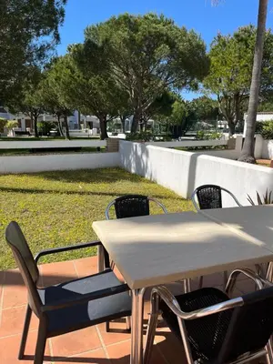 a white table and chairs with trees and grass at Apartamento planta baja con jardín privado in Novo Sancti Petri