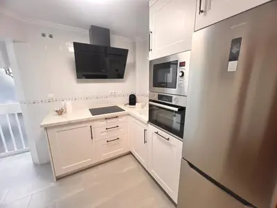a kitchen with white cabinets and a stainless steel refrigerator at Puertas del Mar 1 in Puerto Real