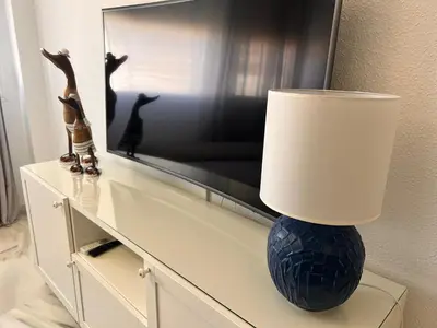 a lamp on top of a dresser with a television at Puertas del Mar 1 in Puerto Real
