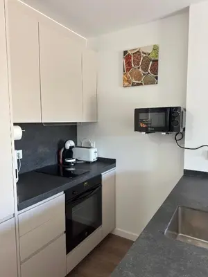 a small kitchen with white cabinets and a sink at Roomy Estudio in Jerez de la Frontera