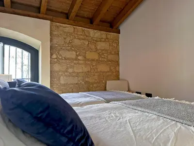 a bedroom with two beds and a stone wall at Sherry de la Riva - Ole Solutions in Jerez de la Frontera