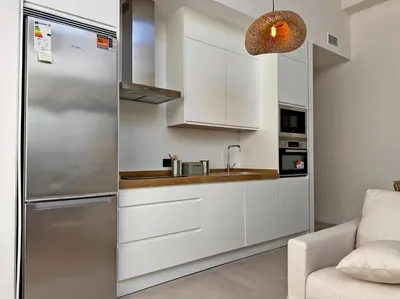 a kitchen with white cabinets and a stainless steel refrigerator at Sherry de la Riva - Ole Solutions in Jerez de la Frontera