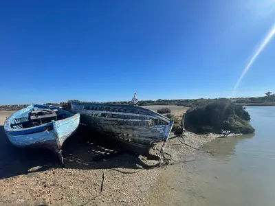 two boats sitting on the shore of a river at Apartclub La Barrosa in Chiclana de la Frontera