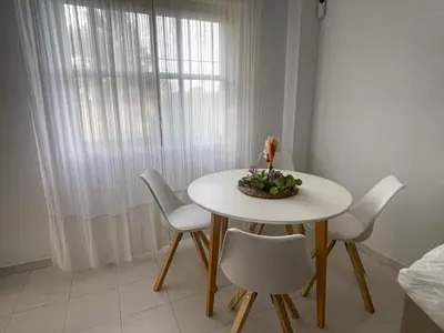a white table with chairs and a bowl of flowers on it at Apartclub La Barrosa in Chiclana de la Frontera