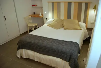 a bedroom with a large white bed and a chair at Tacita Investments,SL in Cádiz