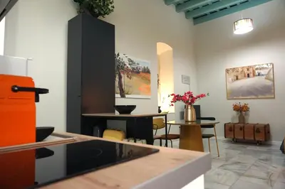 a room with a kitchen and a table with flowers at San Miguel Suite Gallery in Jerez de la Frontera