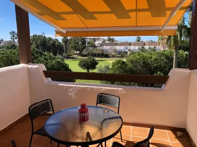 a table and chairs on a balcony with a view at Sonnige und ruhige Ferienwohnung am Golfplatz von Costa Ballena in Rota