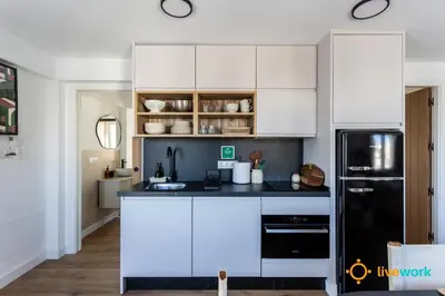 a kitchen with white cabinets and a black refrigerator at La Casa Bonita de la Victoria Livework By Cadiz Time in Cádiz