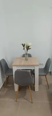 a table with chairs and a vase with flowers on it at Apartamento El Albero in Jerez de la Frontera