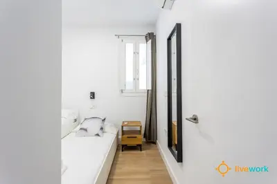 a white bedroom with a bed and a mirror at Cádiz Living by LiveWork in Cádiz