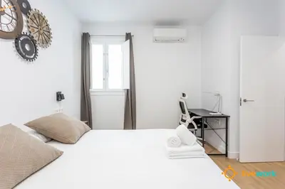 a white bedroom with a large bed and a desk at Cádiz Living by LiveWork in Cádiz