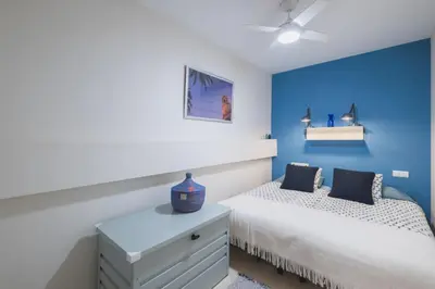 a bedroom with blue walls and a bed and a dresser at Cadizz Anda La Luz Tu lugar en El Puerto Santa María centro ciudad in El Puerto de Santa María