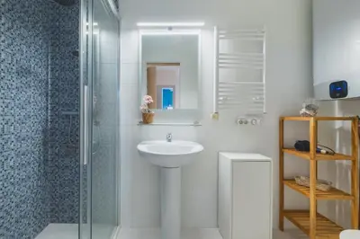 a white bathroom with a sink and a shower at Cadizz Anda La Luz Tu lugar en El Puerto Santa María centro ciudad in El Puerto de Santa María