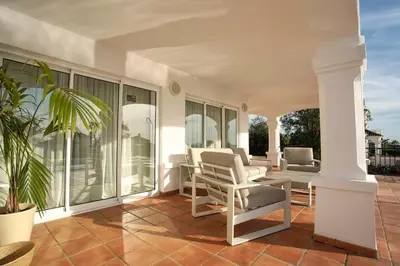 a porch with chairs and a table and windows at Villa 211 by Villamya in Vallejas