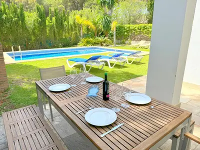 a wooden table with plates and a bottle of wine at Villa el Cenador, Urb Roche Conil in Roche