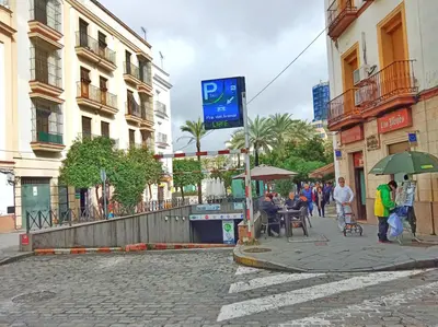 a street with people sitting at tables and an umbrella at Casa Remedios in Jerez de la Frontera