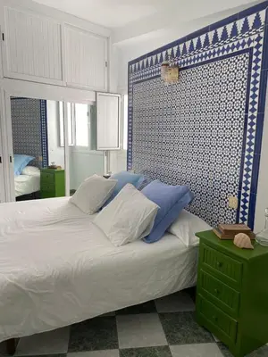 a bedroom with a large bed with blue and white pillows at Casa Michel in Chipiona