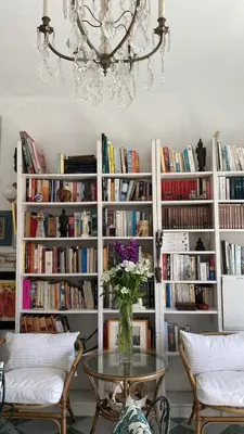 a vase of flowers on a table in a room with books at Casa Michel in Chipiona