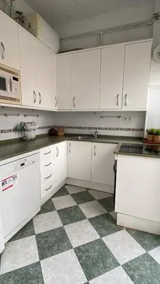 a kitchen with white cabinets and a checkered floor at Casa Michel in Chipiona