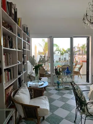 a living room with bookshelves and a table and chairs at Casa Michel in Chipiona
