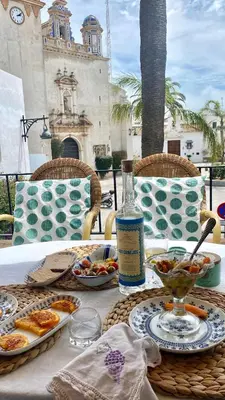 a table with plates of food and a bottle of wine at Casa Michel in Chipiona