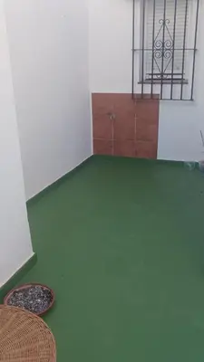 an empty room with a green floor and some chairs at casa andaluza 109 in Novo Sancti Petri