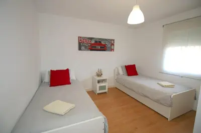two beds in a white room with red pillows at Buleria in Jerez de la Frontera