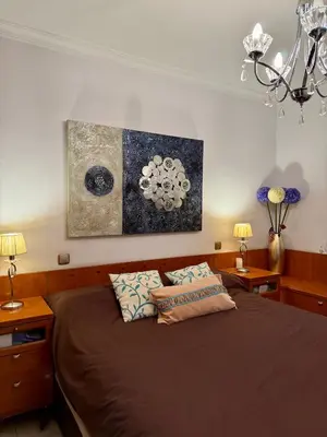 a bedroom with a bed with two lamps and a painting at Grand Beachfront Apartament - Cadiz in Cádiz