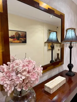 a vase of pink flowers on a table in front of a mirror at Grand Beachfront Apartament - Cadiz in Cádiz