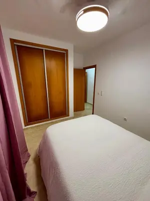 a bedroom with a white bed and a cabinet at Apartamento MAREMIA in San Fernando