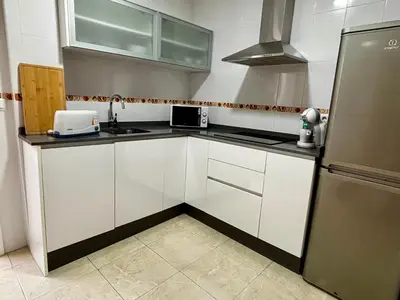 a kitchen with white cabinets and a sink and a refrigerator at Apartamento MAREMIA in San Fernando