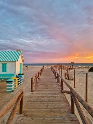 a wooden boardwalk leading to a building on the beach at Apartamento MAREMIA in San Fernando