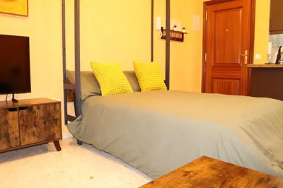 a bedroom with a bed with yellow pillows and a television at Apartamento La Venencia II in Jerez de la Frontera