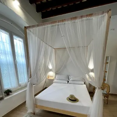 a bedroom with a canopy bed with a hat on it at Apartamentos turísticos CASA de los BALCONES in Chipiona
