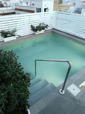a swimming pool with a metal hand rail in it at Apartamentos turísticos CASA de los BALCONES in Chipiona
