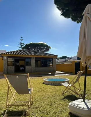 two chairs and an umbrella in front of a house at Villa Atlántida-Playa La Barrosa in Chiclana de la Frontera