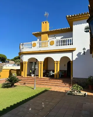 a large white house with yellow columns at Villa Atlántida-Playa La Barrosa in Chiclana de la Frontera
