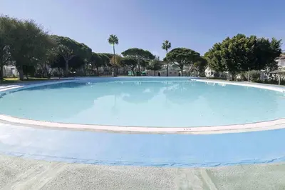 a large blue pool with trees in the background at La Almadraba in Novo Sancti Petri