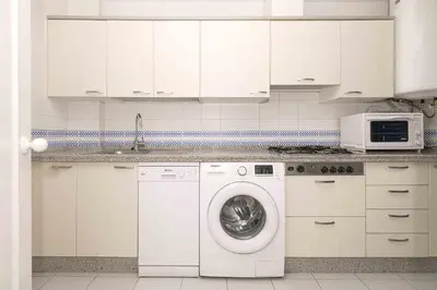 a kitchen with a washing machine and a microwave at La Almadraba in Novo Sancti Petri