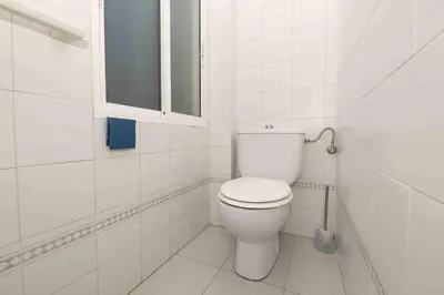 a white bathroom with a toilet and a window at La Almadraba in Novo Sancti Petri